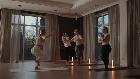 A-group-of-women-is-engaged-in-stretching-and-balance-with-an-instructor-in-a-beautiful-hall-with-large-windows.-Healthy-lifestyle-group-classes.-Joint-training-a-common-spirit